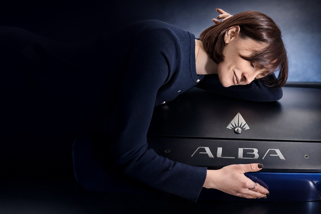 Ragazza appoggiata con eleganza al cofano che mostra il logo del cart elettrico di lusso Alba 2SC colore Royal Blue, veicolo a zero emissioni dal design esclusivo,